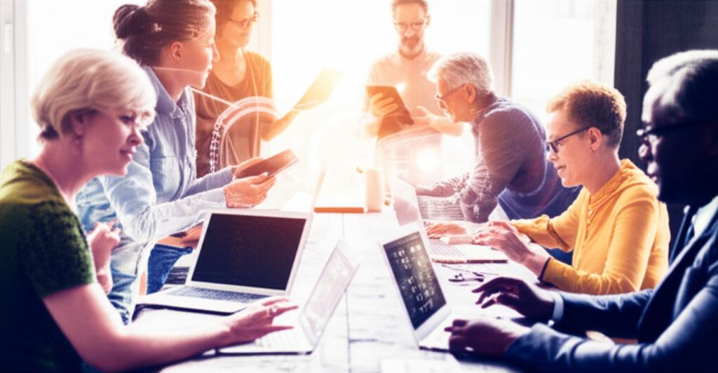 다양한 연령대의 남성과 여성들이 노트북, 태블릿, 스마트폰으로 빛나는 AI 인터페이스와 상호작용하는 활기찬 모습. 미래 지향적인 협업 공간에서 AI를 통한 연결과 역량 강화를 강조합니다.